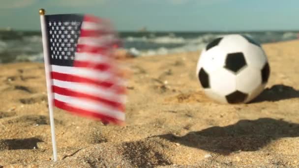 Pelota de fútbol en la playa y la bandera de EE.UU. . — Vídeos de Stock