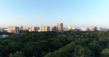 Anteni - City park, yeşil ağaçlar ve yüksek binalar.