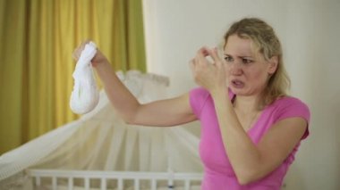 İğrenme ile genç bir kadın bir bebek bezi tutuyor