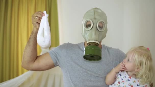 A man in a gas mask holding a baby and a diaper — Stock Video