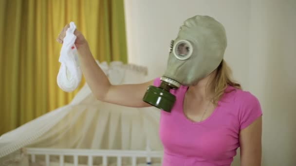 A woman in a gas mask looks disgustedly at the childrens diaper — Stock Video