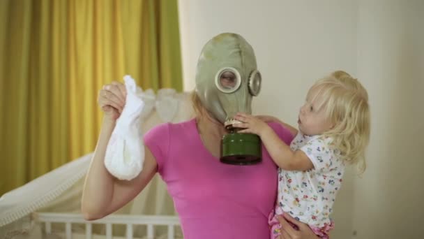 Een vrouw in een gasmasker, met een baby, houden een luier — Stockvideo