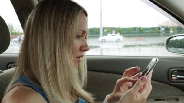 Una mujer en el coche utiliza un teléfono inteligente . — Vídeo de stock