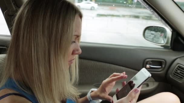 Hermosa mujer en el coche utiliza un teléfono inteligente . — Vídeos de Stock