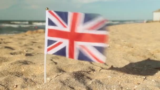 Kumlu bir plaj üzerinde Büyük Britanya bayrağı. — Stok video