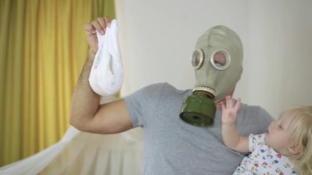 Ein Mann in Gasmaske mit einem Baby und einer schmutzigen Babywindel. — Stockvideo