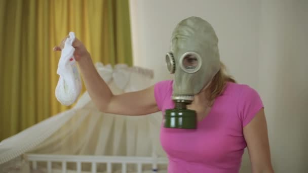 A woman in a gas mask and a dirty baby diaper. Young mother. — Stock Video