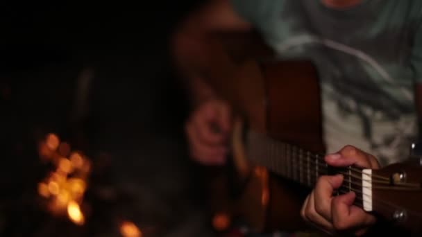 En man spelar gitarr. Natt, brasa, gitarr. — Stockvideo