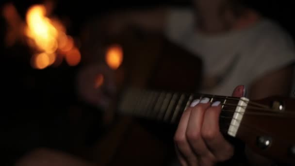 Une femme joue de la guitare près du feu la nuit . — Video