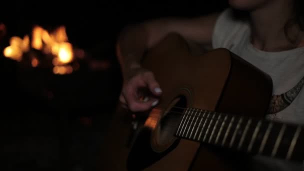 Una mujer toca la guitarra en el fondo de un fuego . — Vídeo de stock