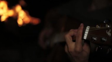 Bir adam bir gitar çalan geceleri ve ateşin.