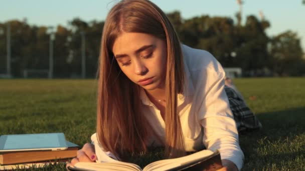 Νεαρή Όμορφη Γυναίκα Διαβάζει Ένα Βιβλίο Στο Πάρκο — Αρχείο Βίντεο