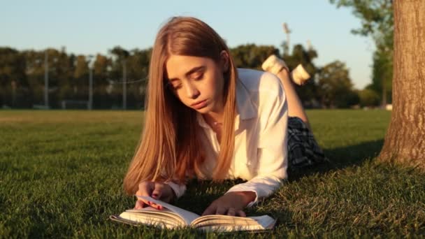 Young girl student in the park reading a book — Stock Video