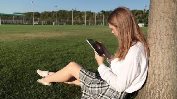 Jovem com um tablet no parque . — Vídeo de Stock