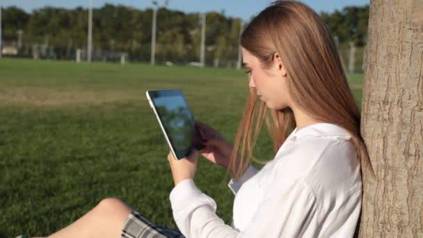 Νεαρή κοπέλα με έναν υπολογιστή tablet στο πάρκο. — Αρχείο Βίντεο