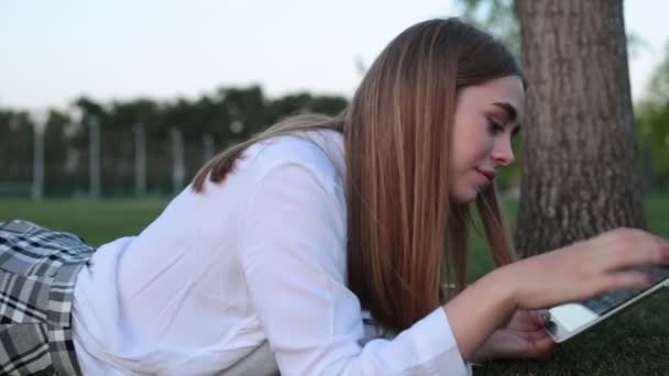 Jeune femme avec un ordinateur tablette sur l'herbe . — Video