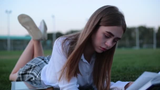 Una colegiala o estudiante en un parque leyendo un libro . — Vídeo de stock