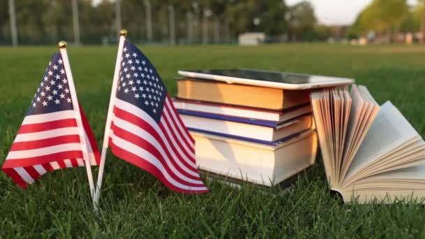 Libros y la bandera de Estados Unidos en el césped. Estudiar en América . — Vídeo de stock