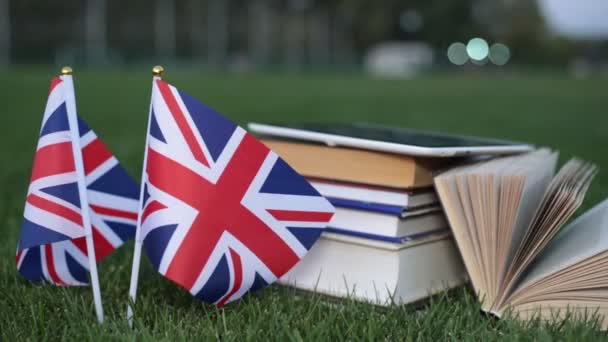 Educación en Inglaterra, inglés. Bandera de Gran Bretaña y libros sobre la hierba . — Vídeo de stock