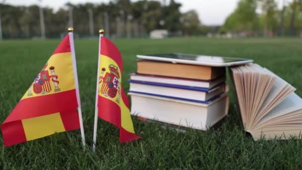 Spanyol nyelv és az oktatás. Spanyolország és könyvek a füvön zászlaja. — Stock videók