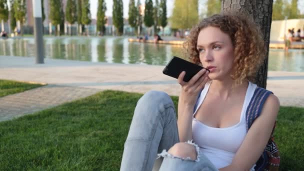 Hermosa joven con un teléfono inteligente en el parque . — Vídeos de Stock