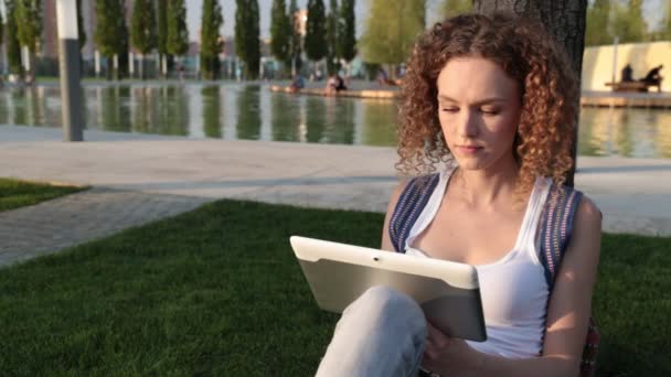 Jovem mulher moderna com um tablet no parque . — Vídeo de Stock