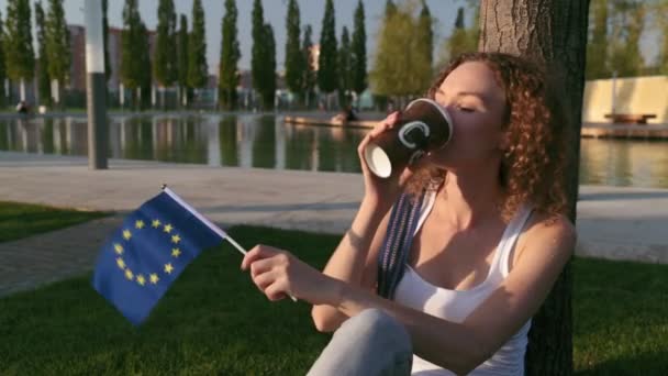Όμορφη γυναίκα σε ένα πάρκο με τη σημαία της Ευρωπαϊκής Ένωσης. — Αρχείο Βίντεο