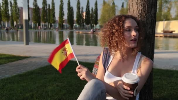Gyönyörű női turista a parkban a Spanyolország lobogója. — Stock videók