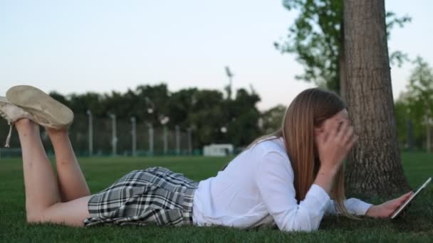 Sexy estudiante femenina con tableta en el parque . — Vídeos de Stock