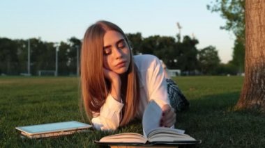 Güzel genç kız öğrenci parkta bir kitap okuma.