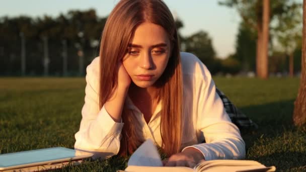 Hermosa joven estudiante leyendo un libro . — Vídeos de Stock