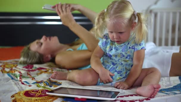 Uma mulher com um smartphone e uma criança com um tablet . — Vídeo de Stock