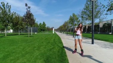 Tekerlekli paten parkta sürme genç güzel kadın.