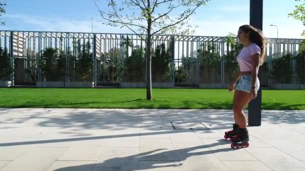 Joven mujer deportiva patinando, cámara lenta. Chica en los rodillos en el parque . — Vídeos de Stock