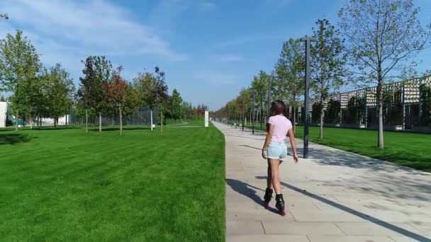 Gadis yang berguling di taman. Wanita muda bersepatu roda, gerakan lambat . — Stok Video