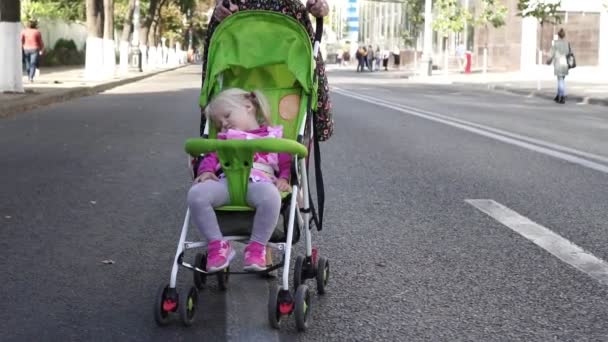 Γυναίκα και παιδί με το μωρό μεταφορά. Μαμά βόλτες με το παιδί στο δρόμο. — Αρχείο Βίντεο