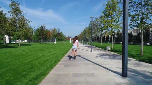 Krásná žena na kolečkových bruslích v parku. Dívka jezdí na kolečkových bruslích. — Stock video