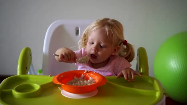 Маленька дитина їсть за дитячим столом — стокове відео