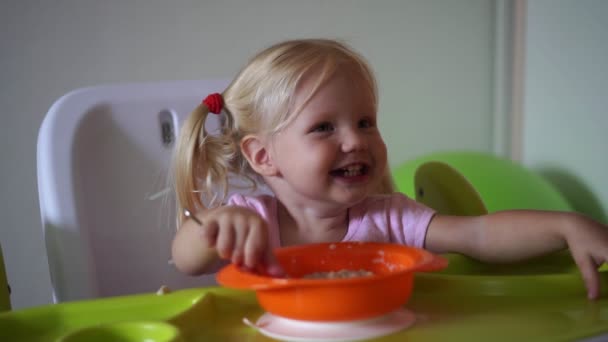Маленька дитина їсть з апетитом за столом . — стокове відео