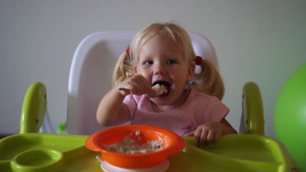 Menina comendo mingau de cereal na mesa . — Vídeo de Stock