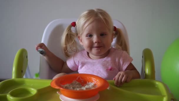 Μικρό μωρό τρώει στο σπίτι. Το παιδί τρώει το χυλό στο τραπέζι. — Αρχείο Βίντεο