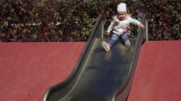 Ребёнок скатывается с холма. Девушка катается на горке по детской площадке . — стоковое видео