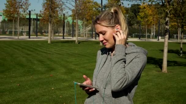Kadın atlet kulaklıklar bir smartphone kullanarak müzik dinlemek. — Stok video