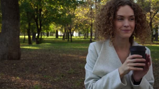 Mujer joven en el parque de otoño tomando café . — Vídeos de Stock
