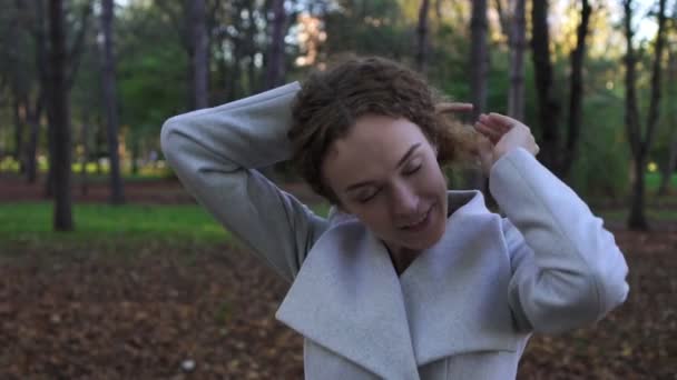 Retrato de una joven hermosa mujer con el pelo rizado en el parque de otoño . — Vídeos de Stock