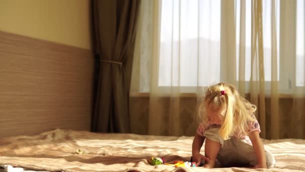 Ein kleines Kind spielt mit Spielzeug auf dem Bett. — Stockvideo