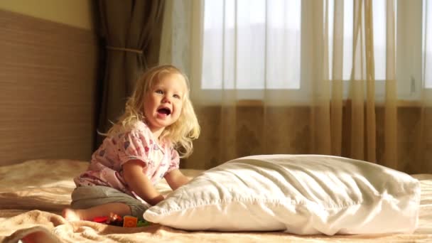 Pequena menina na cama brincando com brinquedos, câmera lenta . — Vídeo de Stock