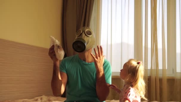 Een jonge vader in een gasmasker houden een vuile babys luier. — Stockvideo