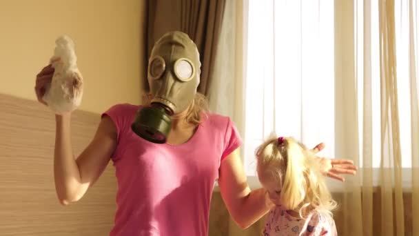 Een vrouw in een gasmasker met walging houdt een vuile baby luier. — Stockvideo