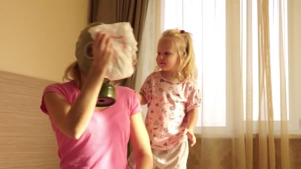A woman in a gas mask changes a dirty baby diaper with disgust. Mother and child. — Stock Video